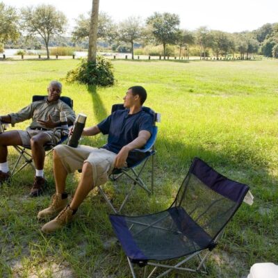 Two men relax outdoors with thermoses.