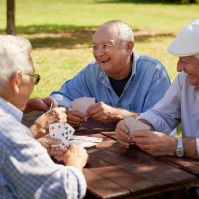 A group of older men playing cards in a park.