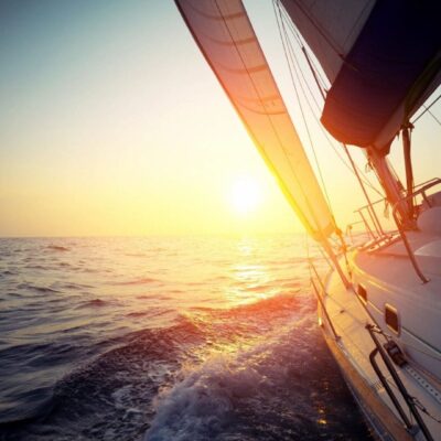 Sailboat sailing into sunset at sea.