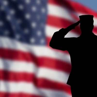 Soldier saluting in front of American flag.