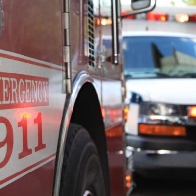 A red and white emergency vehicle is parked in front of a street.