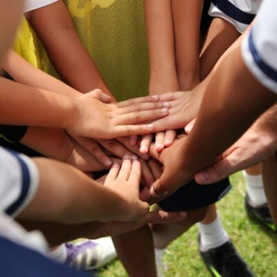 A group of soccer players putting their hands together.