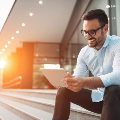 A man sitting on steps looking at his tablet.