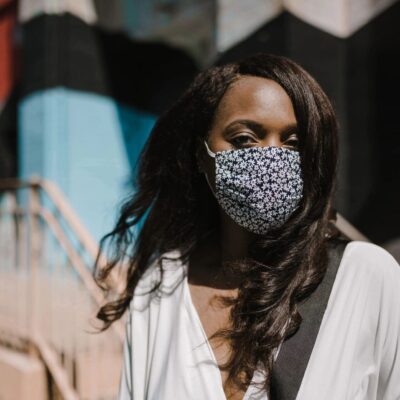 A woman wearing a face mask in front of a building.
