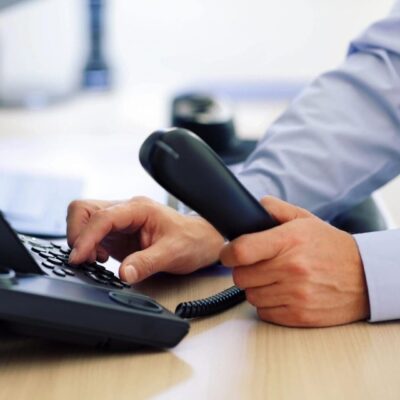 A man is using a telephone on a desk.