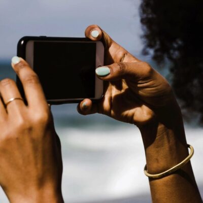 Person taking photo with phone at beach.