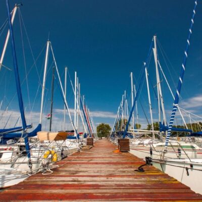 A wooden walkway leading to a marina full of sailboats.