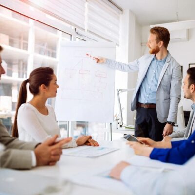 Businessman giving a presentation to a group of people in a meeting room.