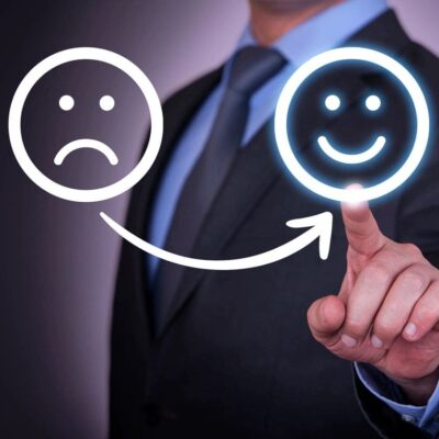 A businessman pointing to a smiley face and a sad face.