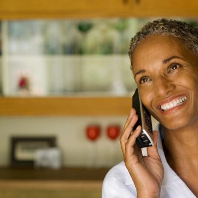 A woman talking on a cell phone in a kitchen.