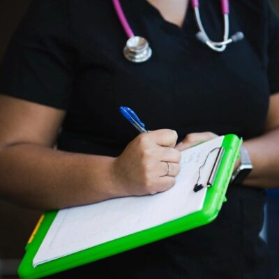 A nurse is holding a clipboard and writing on it.