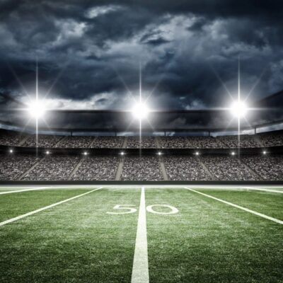 Empty football field under bright stadium lights at night.