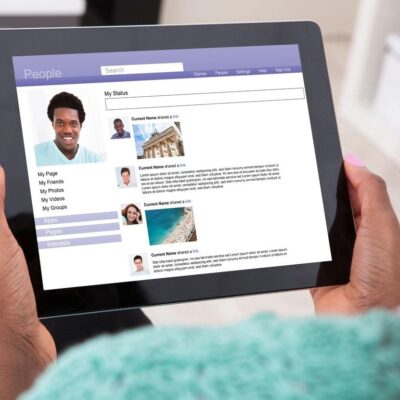 A woman holding an ipad with a person's profile on it.