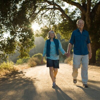 An older couple walking down a dirt road.