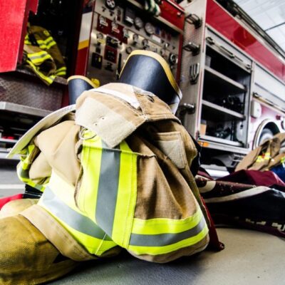 A firefighter's gear is sitting on the floor in front of a fire truck.