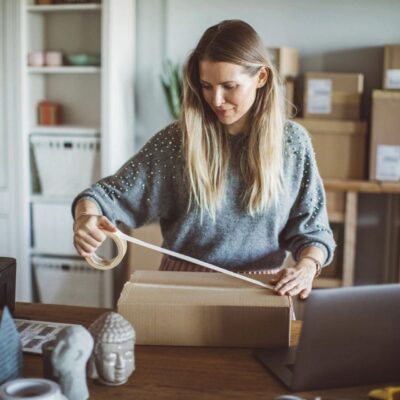 A woman is opening a box in her home office.
