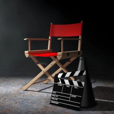 A red director's chair and clapboard on a dark background.