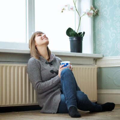 A woman sitting on the floor with a cup of coffee.