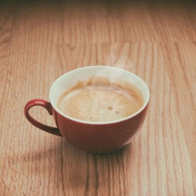 Here's an alt tag for the image: `Steaming coffee in red mug on wood`