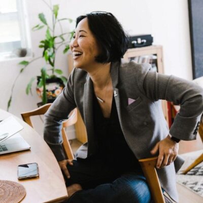 A woman sits at a desk and laughs.