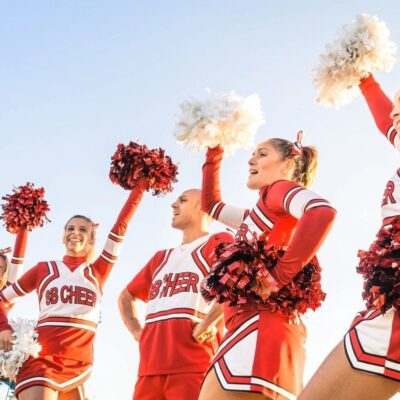 A group of cheerleaders are standing together and one is holding pom poms.