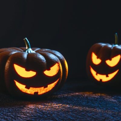Two carved pumpkins with scary faces on a dark background.