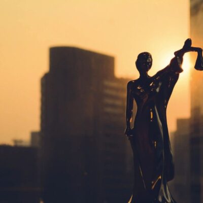 A statue of a woman holding a scale in front of a city.