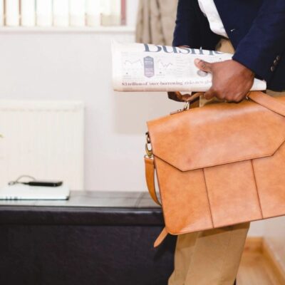 Businessperson holding briefcase and newspaper.