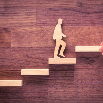 Wooden figure climbing career ladder.