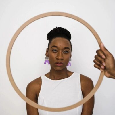 A woman holding a hoop in front of a white wall.