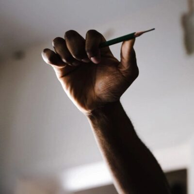 A hand holding a pencil up in the air.