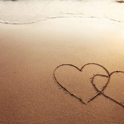 Two hearts drawn in the sand on a beach.