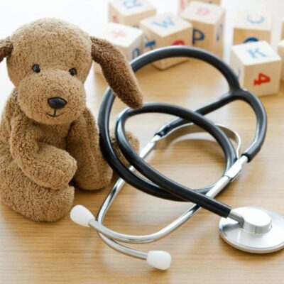 A stethoscope and a teddy bear on top of the table.