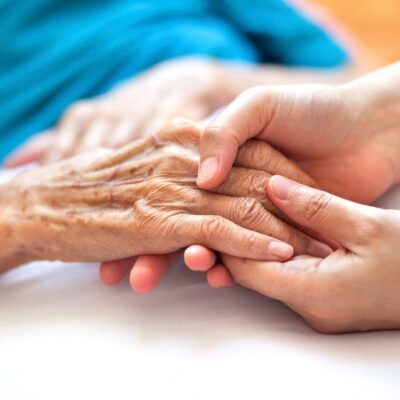 A woman is holding an elderly woman's hand.