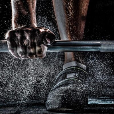 Close-up of hands gripping a barbell with chalk dust in the air.