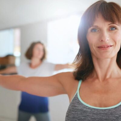 Two women practicing yoga poses indoors, focused and calm.