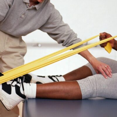Physical therapist assisting patient with resistance band.