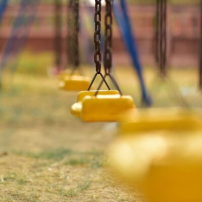A group of yellow swings in a playground.