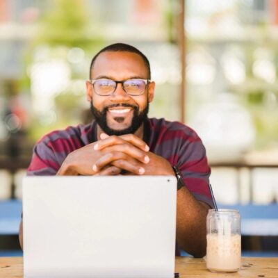 A black man sitting at a table with a laptop.