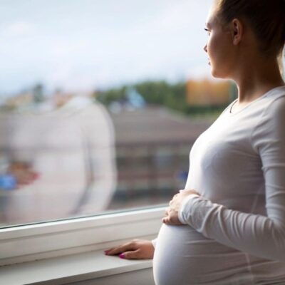 Pregnant woman looking out window.