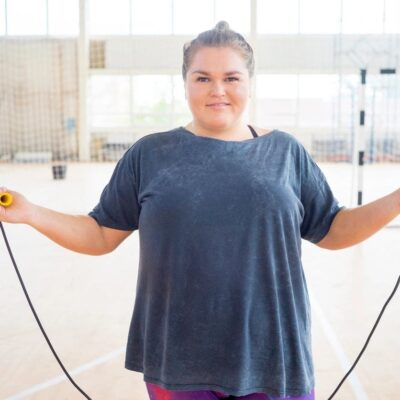Woman smiling while skipping rope indoors.
