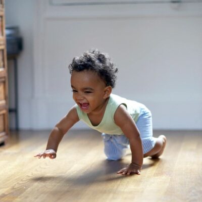 A baby crawling on the floor in a living room.