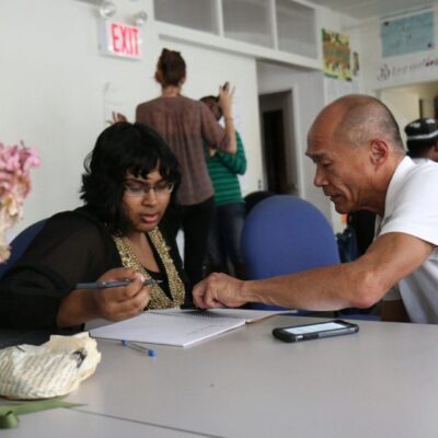 A man and a woman sitting at a table in a classroom.