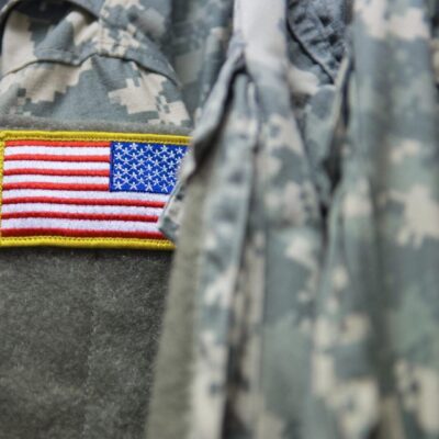 A close up of an american flag on a camouflage uniform.