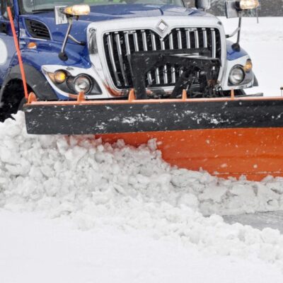 A snow plow driving down a snowy road.