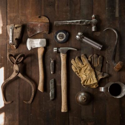 A collection of vintage tools and gloves on a wooden surface.