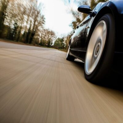 A black car driving down a country road.