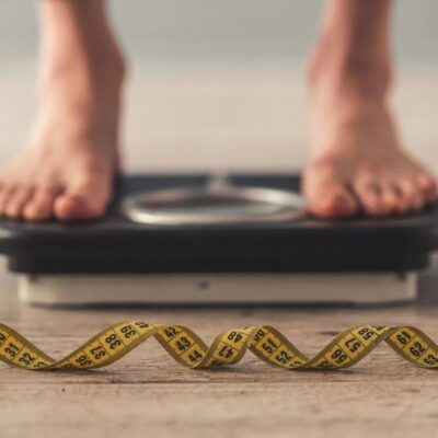 A person standing on a weight scale with a yellow tape.