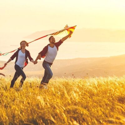 Family flying kite in sunset field.