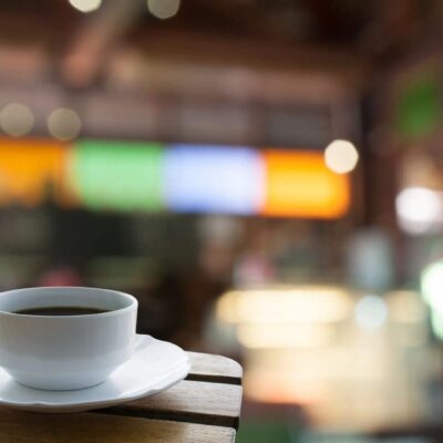 Cup of coffee on wooden table, blurred background.